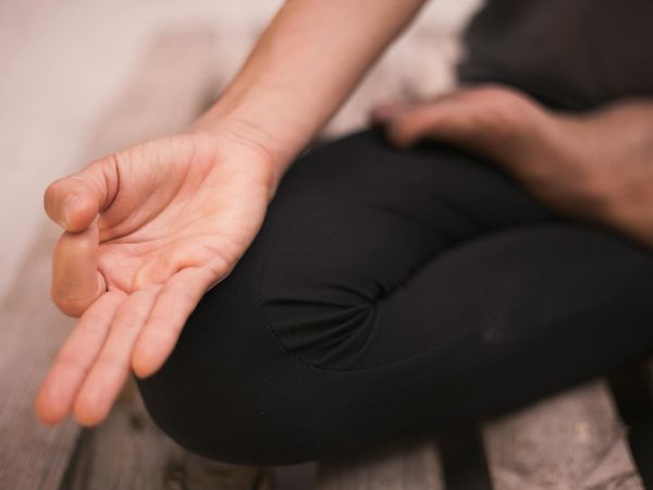 Close-up of a person's hands in a meditative mudra pose.